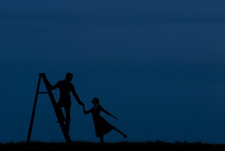 Man Standing on Ladder While Holding Woman's Hand, Silhouette