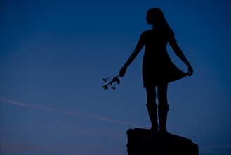 Girl Standing on Rock Holding Flowers, Silhouette