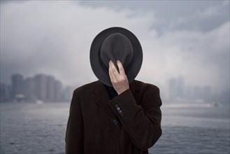 Man with Hat Covering his Face against Cloudy Sky