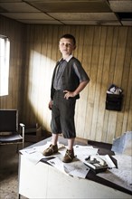 Young Boy Standing on Desk in Abandoned Office