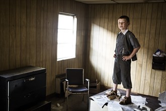 Young Boy Standing on Desk in Abandoned Office