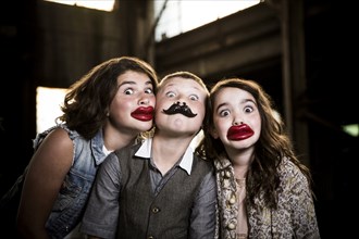 Two Wide-Eyed Girls and Boy Wearing Wax Lips and Making Silly Faces in Abandoned Warehouse