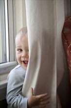 Little Boy Peeking Out From Behind Curtains