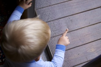 Little Boy Pointing Outside Through Screen Door