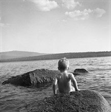Young Boy Climbing Down a Rock in Lake