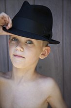 Young Boy Touching Brim of Fedora Hat