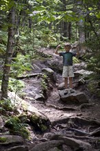 Young Boy Flexing Arm Muscles on Path in Woods