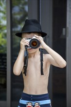 Young Boy Wearing Fedora Hat Taking Picture With Camera
