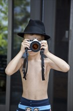 Young Boy Wearing Fedora Hat Taking Picture With Camera