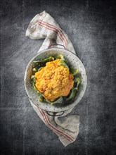 Yellow Cauliflower in Colander with Linen Towel on Stone Grey Surface