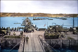U.S. Military Vehicles move ashore across Pontoon Bridge to Omaha Beach from Temporary Mulberry Harbour A, Normandy, France, June 16, 1944