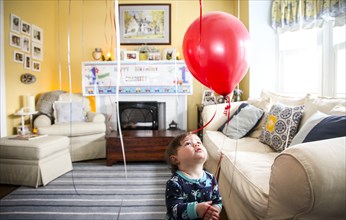 Infant Boy Looking up at Red Balloon in Living Room