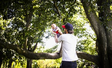 Father Holding up Infant Son in Park