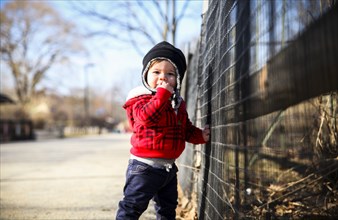 Three-Quarter Length Portrait of Young Boy Standing next to Fence
