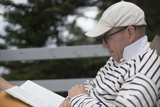 Mid-Adult Man Reading Book on Deck