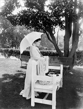 Mrs. Edith Roosevelt, full-length portrait, standing behind bench, facing right, holding umbrella, Photograph by Charles Milton Bell, August 1904