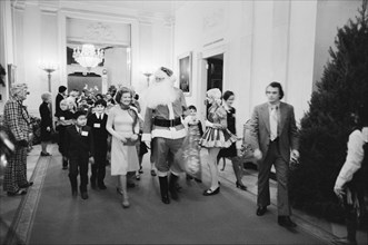 First Lady Betty Ford, Santa Claus, and clowns lead a procession of Diplomatic Corps children at a White House Christmas party, Washington, D.C., USA, photograph by Thomas J. O'Halloran, December 16, ...