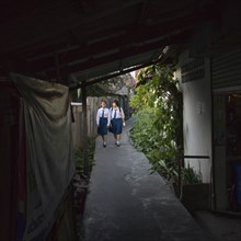 Two Girls in School Uniforms on Narrow Walkway, Bangkok, Thailand