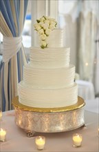 Multi-Tiered Wedding Cake with White Roses Surrounded by Candles
