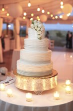 Multi-Tiered Wedding Cake with White Roses Surrounded by Candles