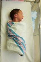 High Angle View of Sleeping Newborn Baby Girl Wrapped in Blanket in Hospital