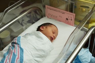 Sleeping Newborn Baby Girl Wrapped in Blanket in Hospital