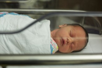 Sleeping Newborn Baby Girl Wrapped in Blanket in Hospital