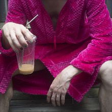 Mid-Adult Man in Pink Robe Sitting Down with Ice Coffee
