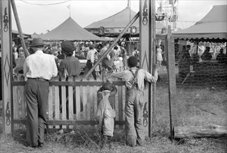 Two African American children watching Greene County Fair through Fence