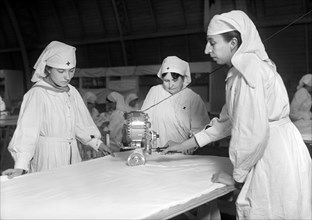 Female American Red Cross Workers cutting Unbleached Muslin for Bias Bandages with Cutting Machine in American Red Cross Workroom for making Surgical Dressings
