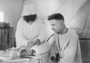 American Red Cross Nurse bandaging arm of Wounded American Soldier