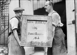 Two Men carrying Box filled with American Red Cross Supplies labeled "Front Parcels" to be delivered to the Front Lines of War