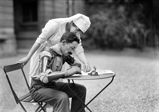 French Mutile with both arms off the elbow writing letter to American Red Cross worker