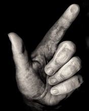 Mid-Adult Woman's Hand with pointed Thumb and Index Finger against Black Background