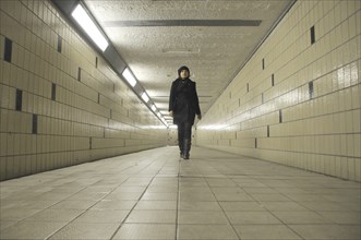 Young Adult Woman Walking through Underground Pedestrian Tunnel