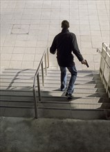 Rear View of Man with Gun walking down Steps