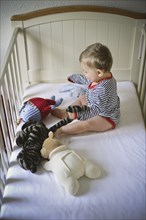 Baby Boy playing with Soft Toys in Crib