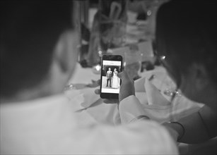 Two People looking at Picture of Wedding Couple on Smart Phone