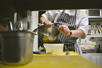 Chef putting Grated Cheese in Plastic Container