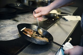 Chef basting Meat in Frying Pan