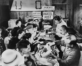 Japanese Americans gather in Police Inspection Room to receive Packages that are being inspected at Detention Facility