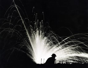 Silhouette of Soldier against Phosphorous Streamers from Bombs Exploding during Night Attack