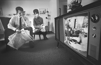 Man and Woman watching Film Footage of Vietnam war on Television in their Living Room