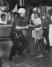 Policeman confronts group of People after night of rioting due to fatal shooting of Teen James Powell by Police Officer Lt. Thomas Gilligan, 126th St. and Seventh Avenue, July 1964