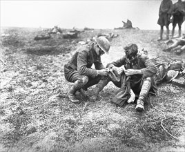 Close-up of Two Soldiers in Uniform sitting on ground examining Clothing for Lice during World War I, Nantillois, 1918
