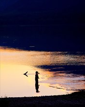 Silhouette of Man Fly-fishing in Lake,,