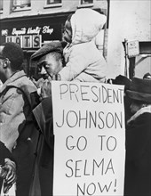 Protester with Child on Shoulders holding Sign Protesting Racism in Selma, Alabama
