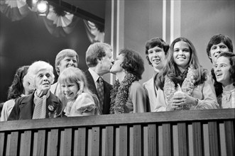Jimmy Carter and Rosalynn Carter kissing, surrounded by family including Amy Carter and Lillian Carter
