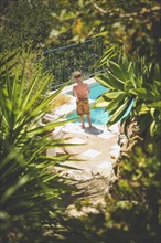 Rear View of Young Shirtless Boy standing near Swimming Pool,