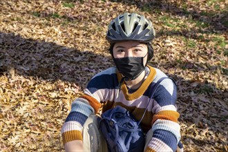 Teen Girl wearing Bicycle Helmet and Protective Mask, half-length seated Portrait